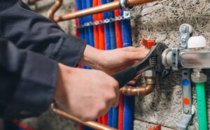 Technician tightening a copper gas pipe connection with a wrench during professional Gas Installation Services, ensuring secure and leak-free fittings.