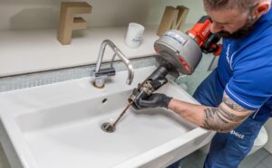 Professional technician using drain cleaning equipment in a bathroom sink, showcasing reliable Drain Cleaning Services for removing clogs and restoring proper water flow.