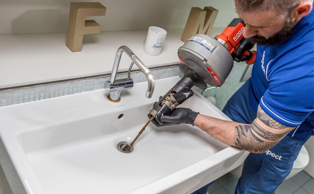 Professional technician using drain cleaning equipment in a bathroom sink, showcasing reliable Drain Cleaning Services for removing clogs and restoring proper water flow.