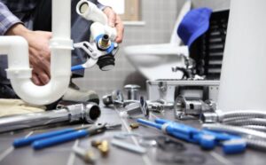 Technician assembling plumbing pipes and fittings under a sink, demonstrating professional Sewer Installation Services with tools and components for efficient drainage setup.