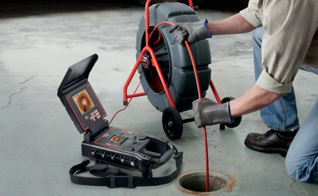 Technician using a camera system to check underground pipes during professional Sewer Line Inspection Services.