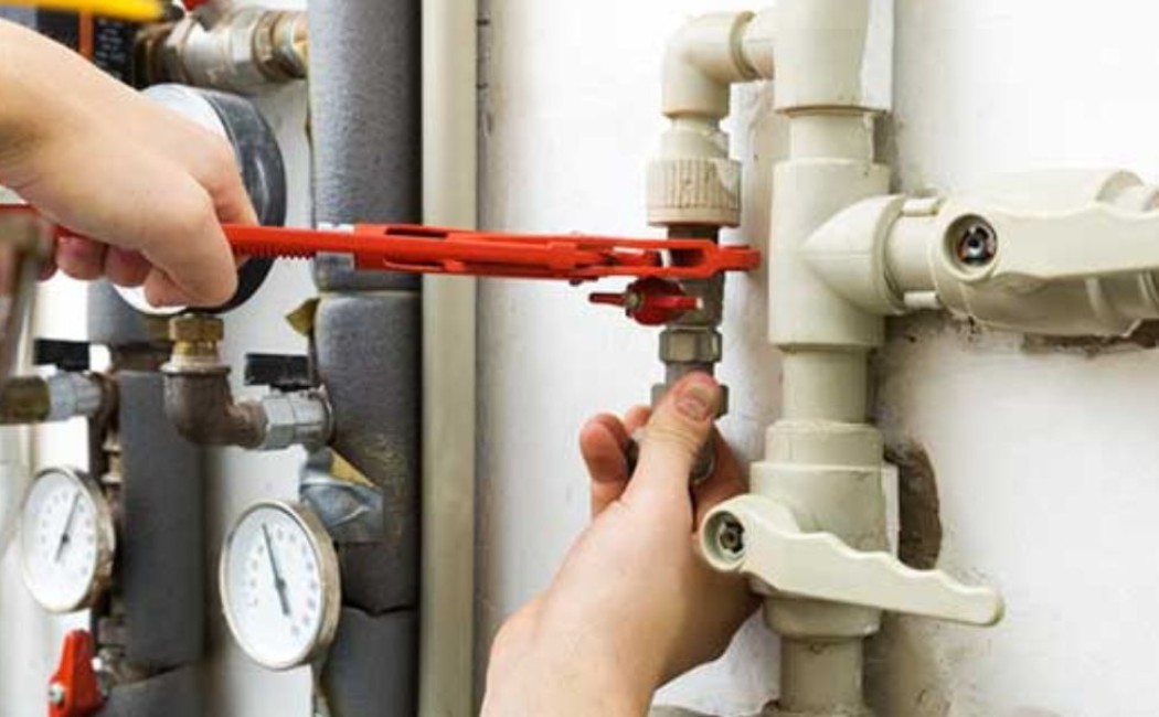 Technician using a wrench to secure pipes and valves during Gas Line Installation in an indoor plumbing system.