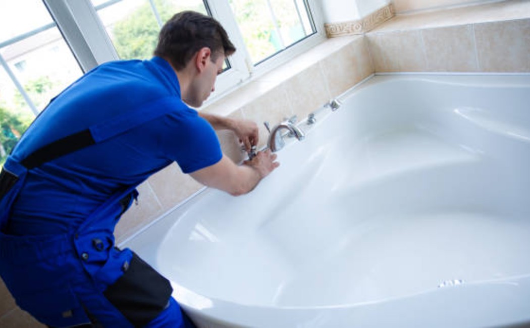 Best Bathroom Plumbing Services for Modern Bathtub Faucet Repair Plumber providing Bathroom Plumbing Services by repairing a bathtub faucet in a modern bathroom near a window.