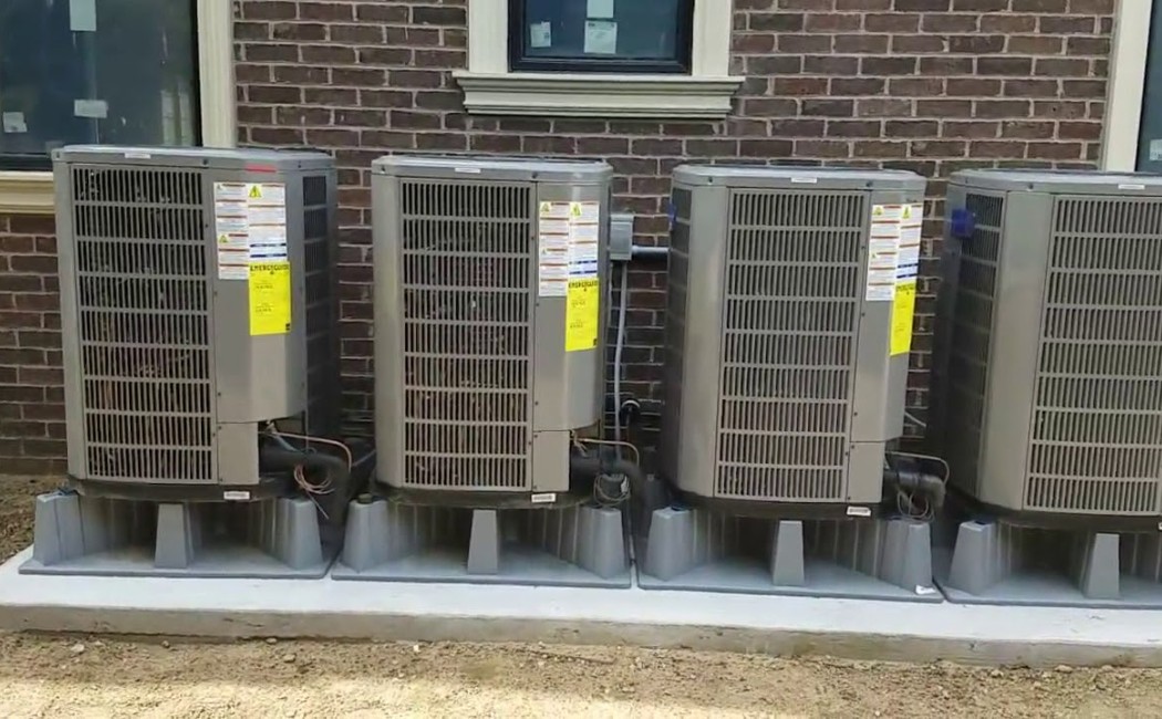 Multiple outdoor air conditioning units installed in a row beside a brick building by an HVAC Installation Company.