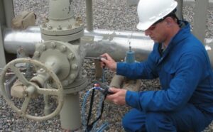Technician performing Leak Detection Services on an industrial pipeline system using specialized equipment.