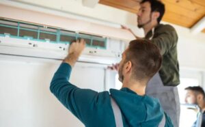 Specialists performing expert HVAC installation while servicing a wall-mounted air conditioning unit indoors