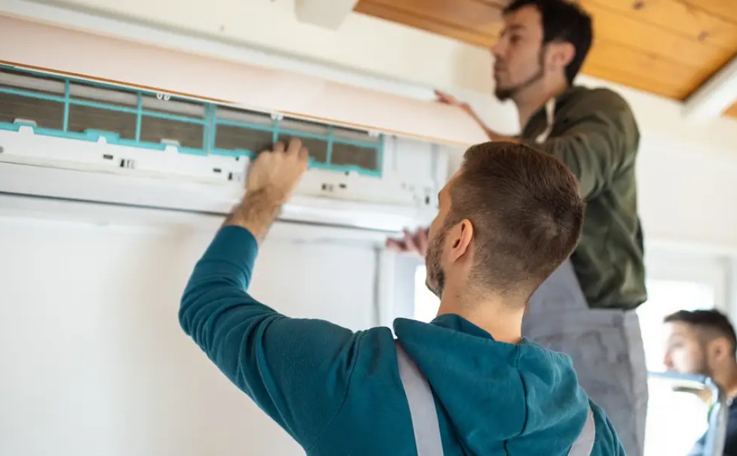 Specialists performing expert HVAC installation while servicing a wall-mounted air conditioning unit indoors